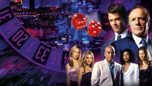 James Caan como Big Ed Deline en la serie Las Vegas, de pie en el lujoso casino Montecito con mirada autoritaria.